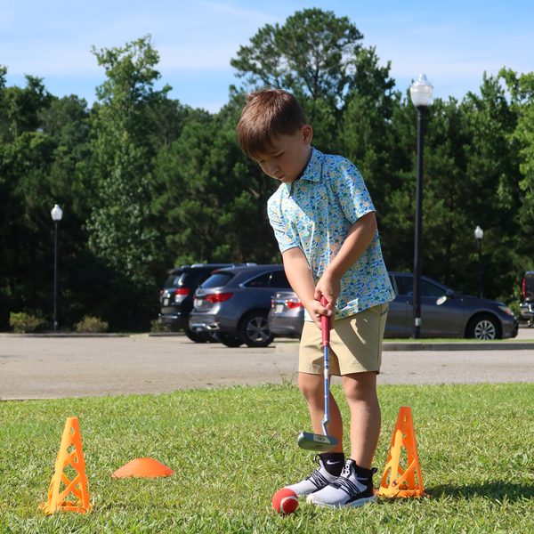 A young golfer lines up a putt between orange cones